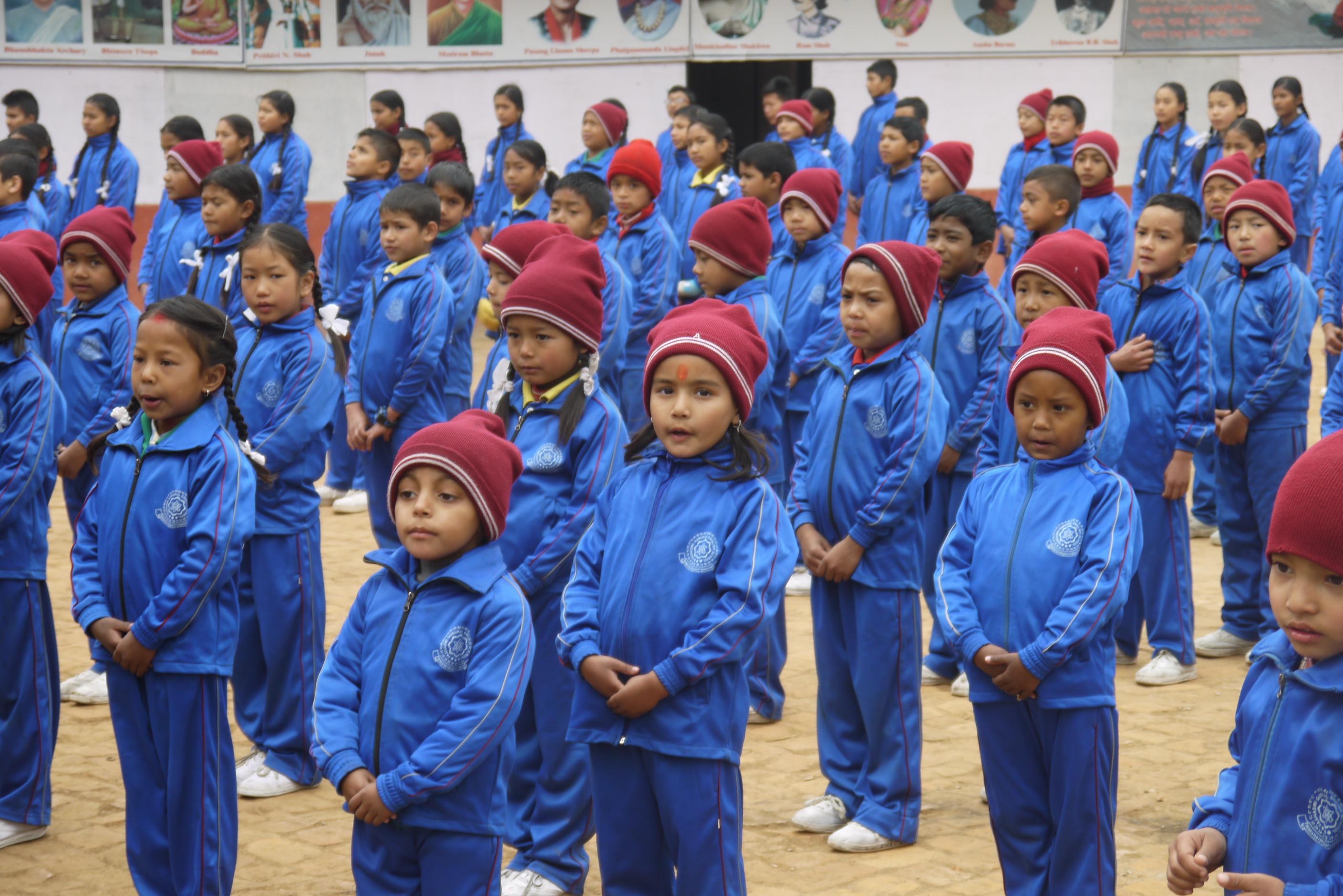 A group of older adults completing childcare volunteer work in Nepal, lead an outdoor activity with young students. A group of volunteers over 50 doing childcare volunteering in Nepal, work with children during an outdoor activity.